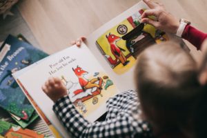 Young Boy Reading Picture Book with Help From An Adult